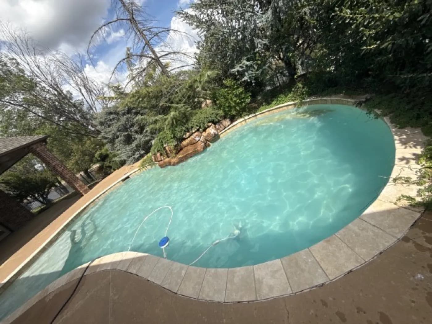 Rock-waterfall pool clearing up after professional green pool recovery in Oklahoma